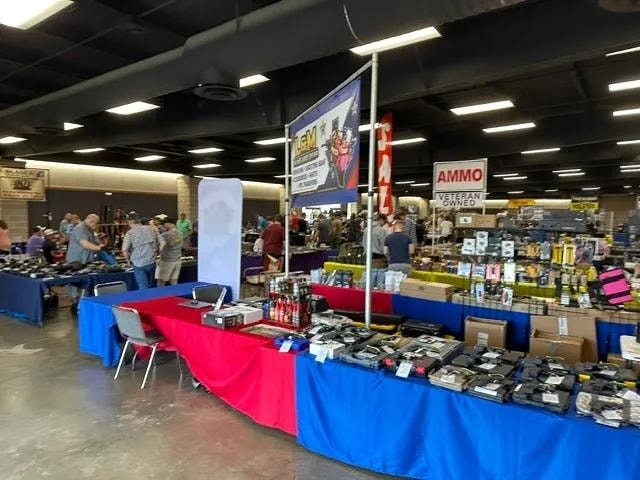 Gun show floor with vendor tables and attendees